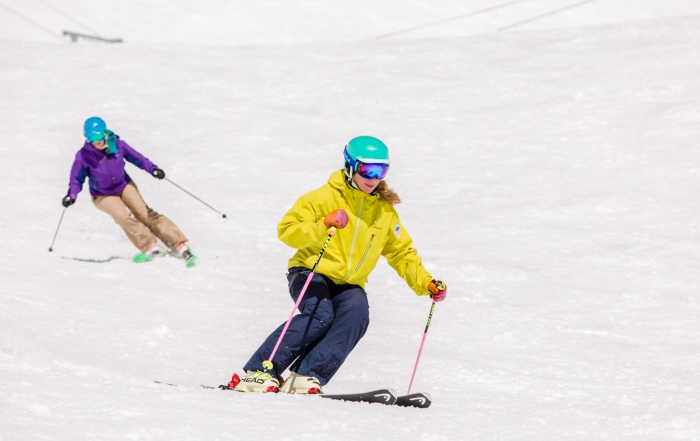 PSIA-AASI National Team Member Robin Barnes demonstrates for her student skiing behind her