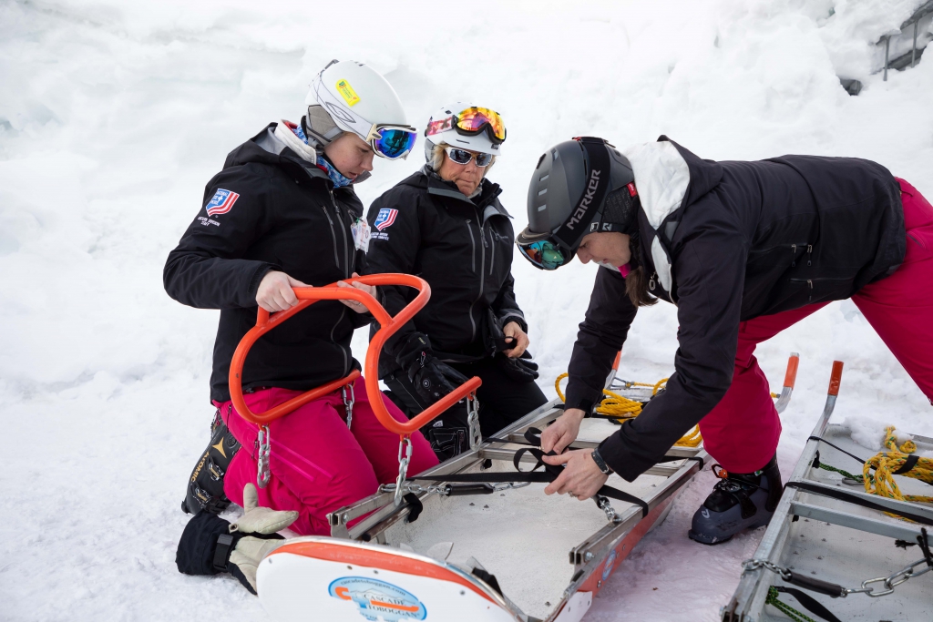 National Ski Patrol members buckle a sled