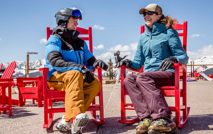 PSIA-AASI ski instructors talk while sitting in red chairs.