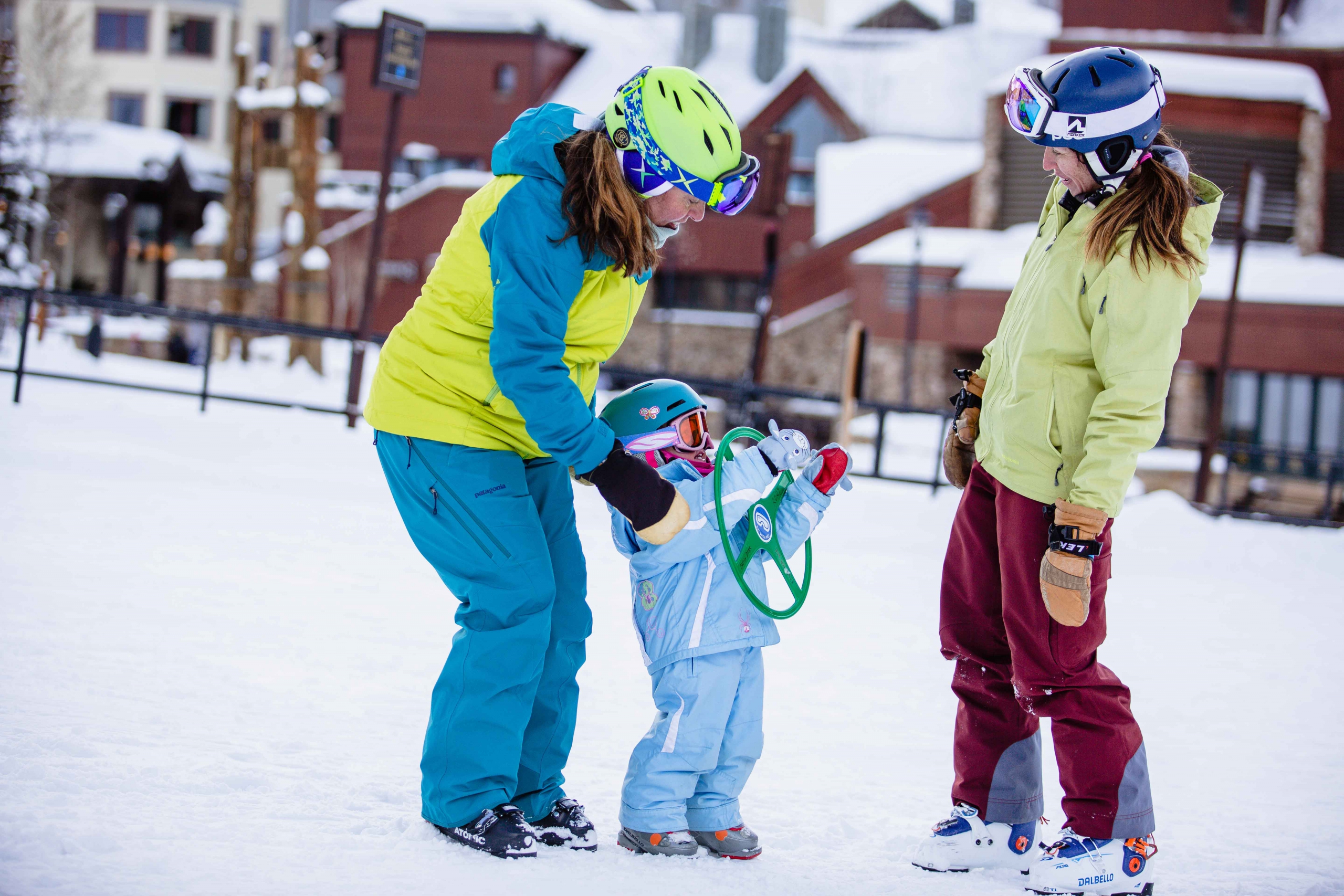 A ski instructor teaches a family and young kids to ski.