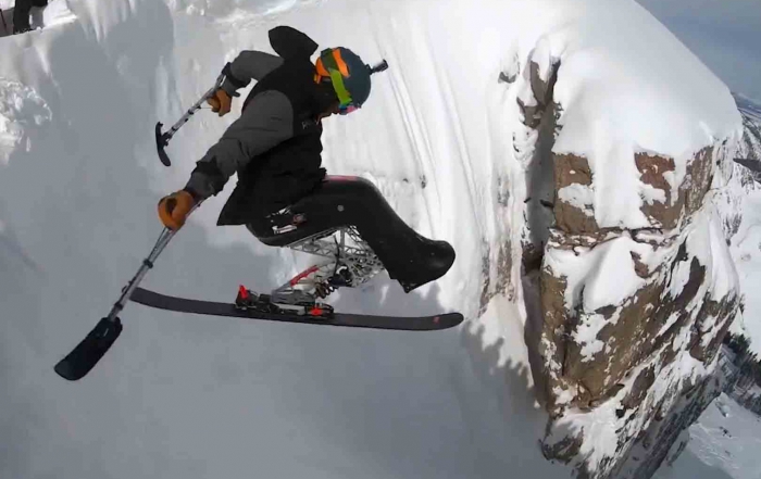 An adaptive skier jumps a steepcliff