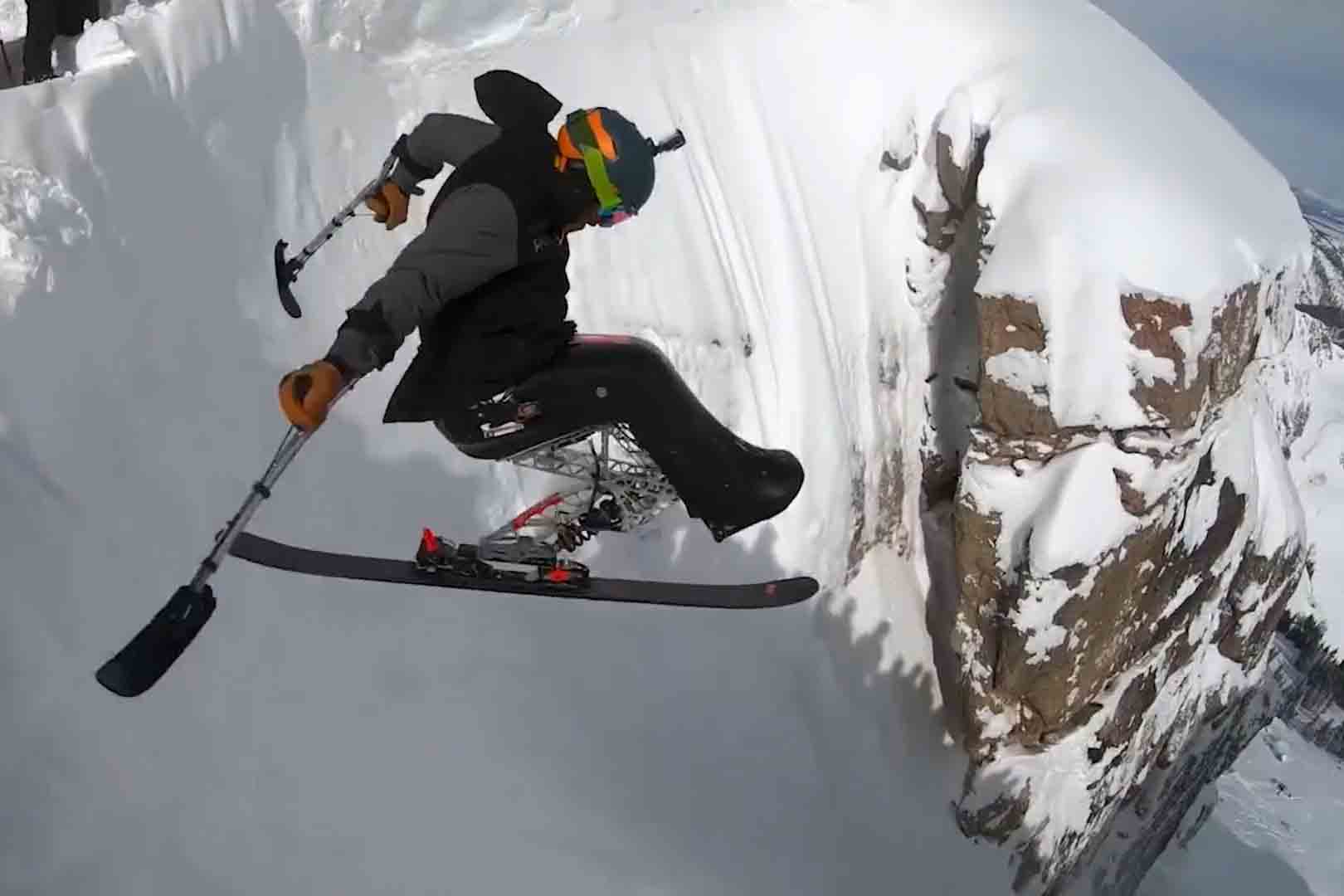 An adaptive skier jumps a steepcliff