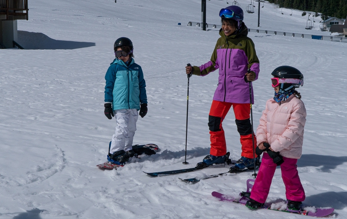 A family skis and snowboard