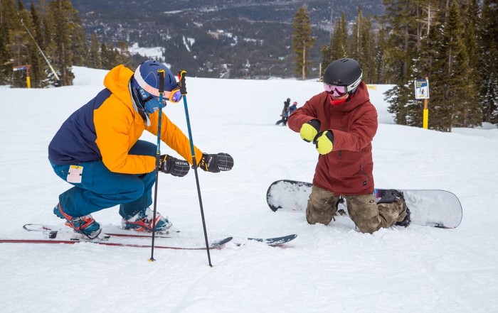 A telemark skier and snowboarder use their hands to show body position and movement on the snow