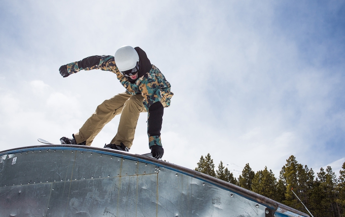 A snowboarder rides over a rainbow rail