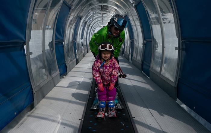 a ski instructor and their student ride the ski carpet