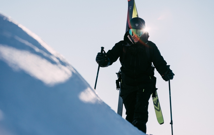 a skier bootpacks with his rossi skis on his backpack