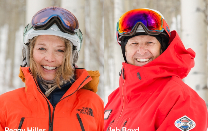 Peggy Hiller and Jeb Boyd pose in the north face snow gear in front of aspen trees in vail colorado with snow on the ground