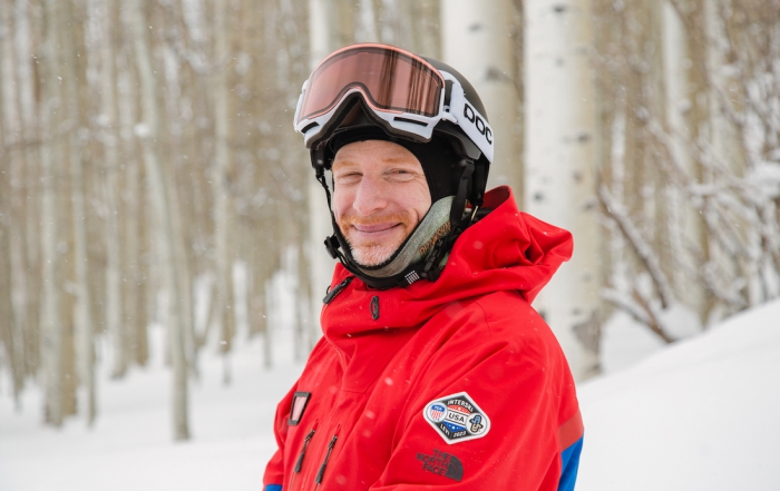 Brian Donovan Team Training PSIA AASI National Team member poses on snow in front of Aspen trees
