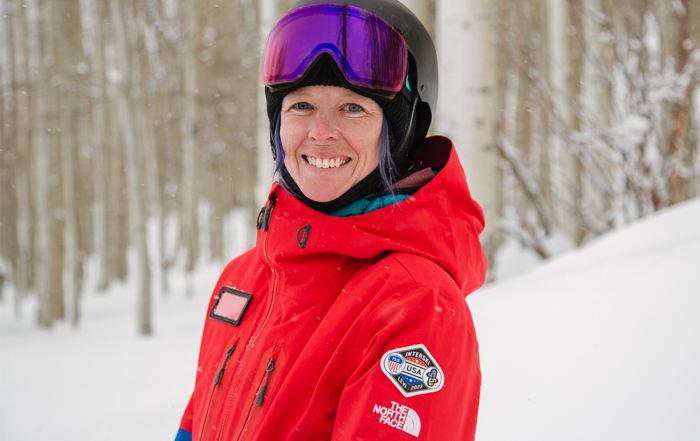 PSIA-AASI National Team member Stephanie Wilkerson poses on snow in front of Aspen trees.