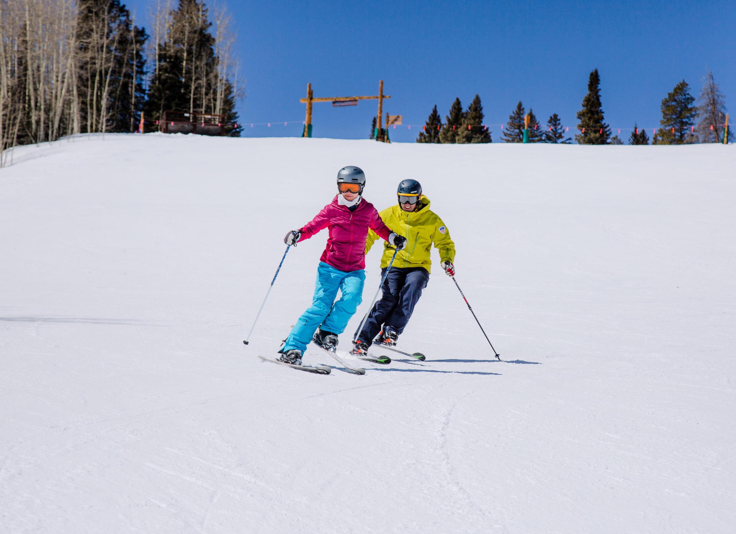 ski instructor skis with students on a groomed slope practicing a drill where they lift the inside skis