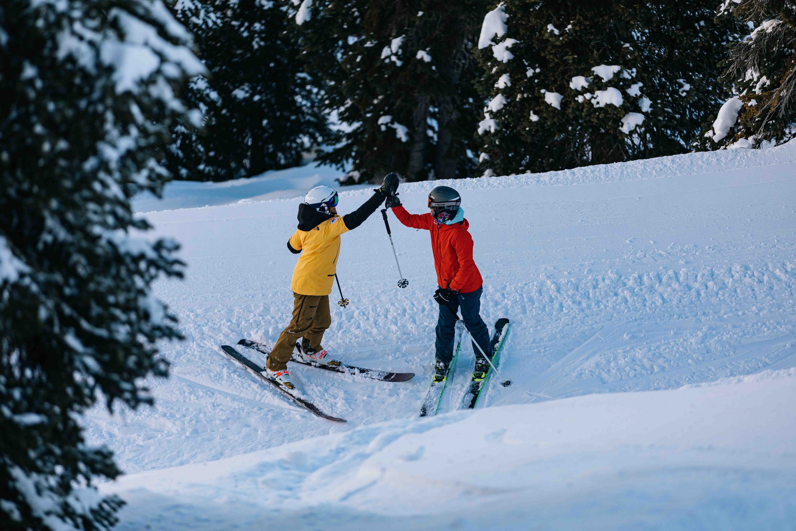 Two skiers high five standing on a catwalk.