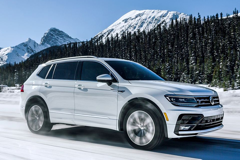 A white Volkswagen drives on a snowy road