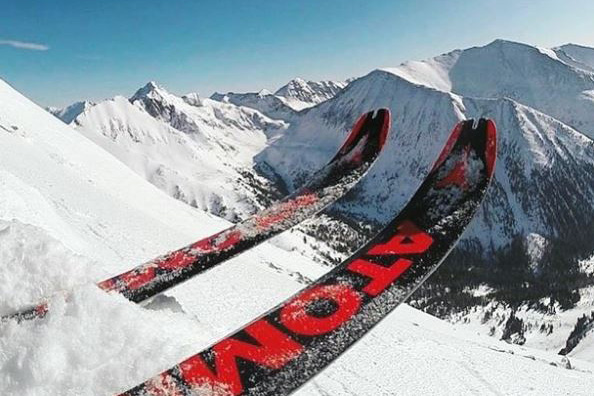 The tips of atomic skis protrude from the snow at the top of a powder run