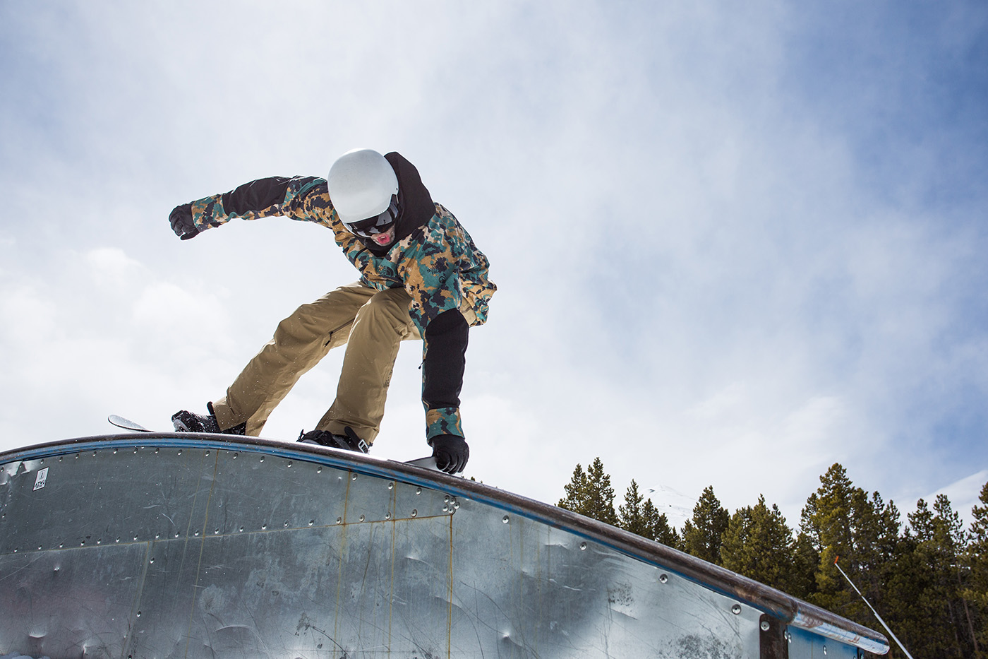 A snowboarder rides over a rainbow rail