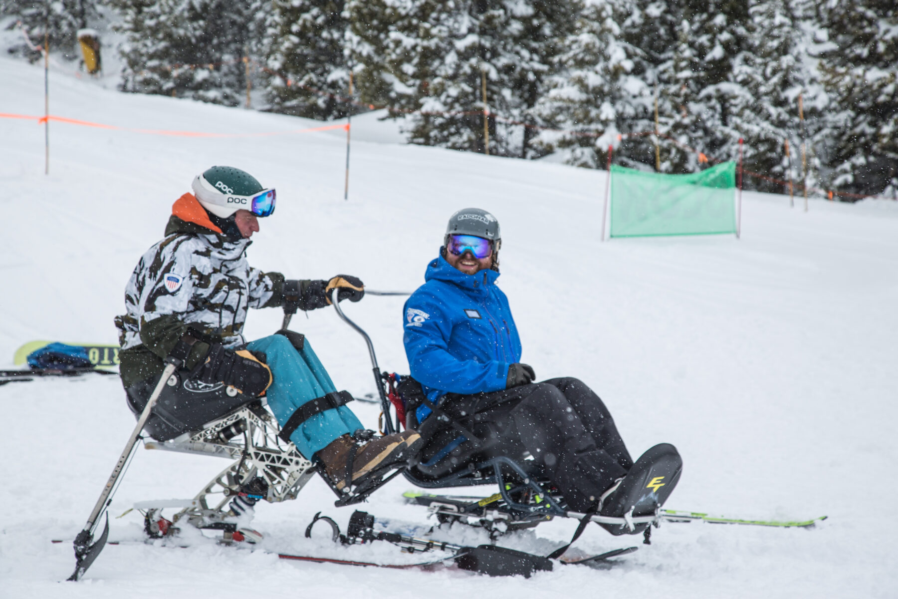 Two adaptive sit skiers.