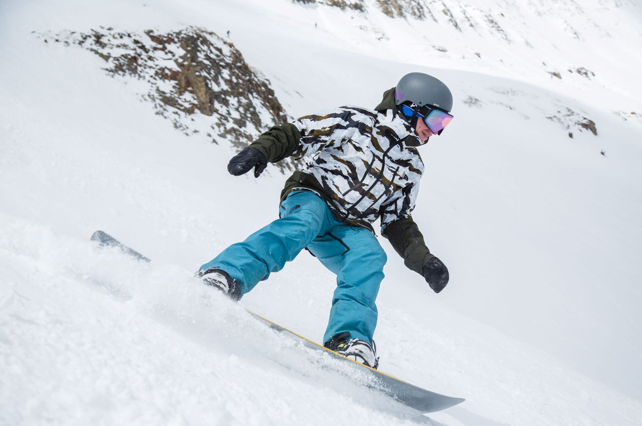 Snowboarder in blue pants carving a turn in snow