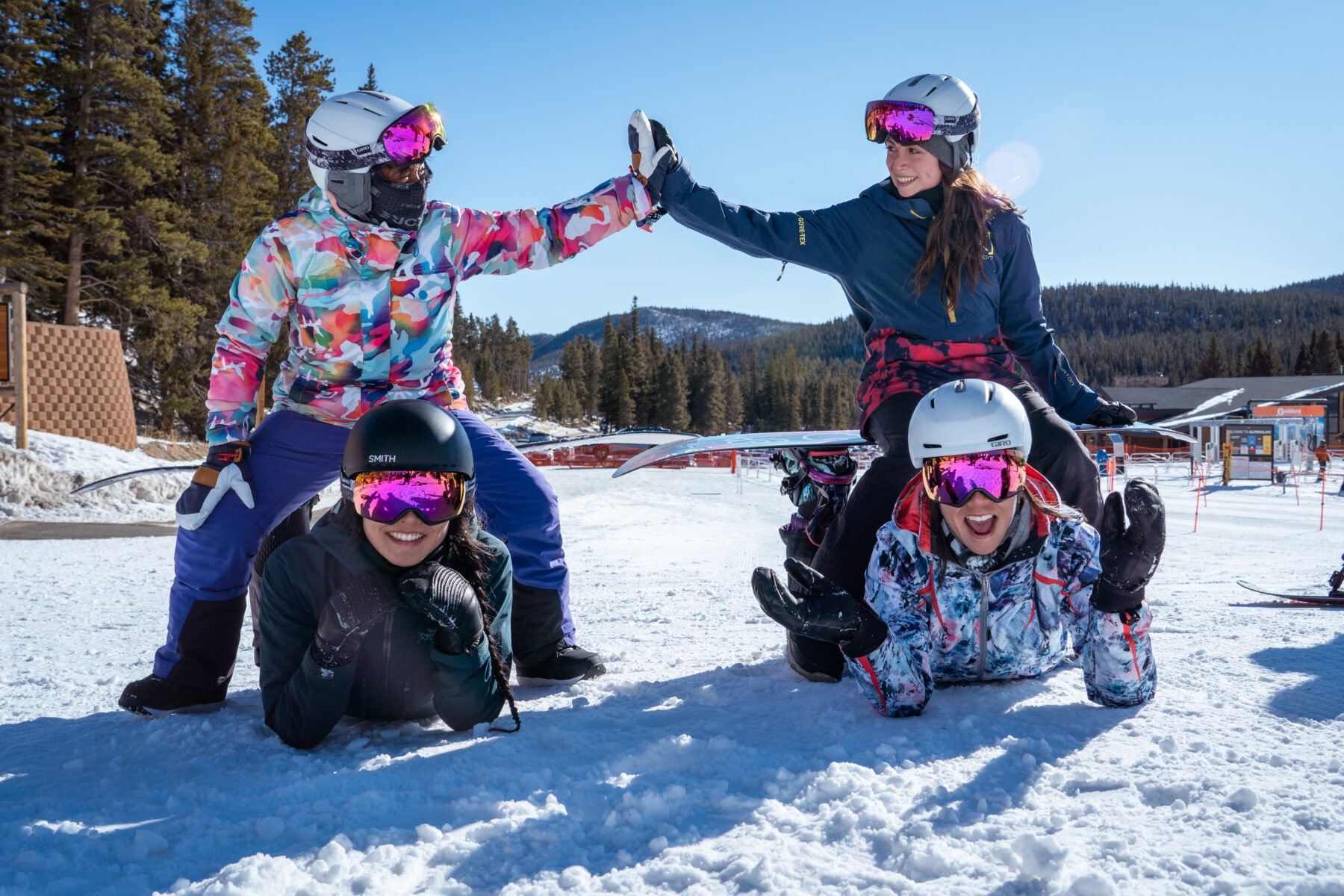 four women snowboarders high fiving